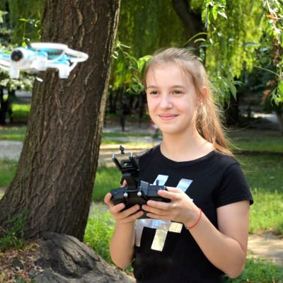 Smiling teen girl using drone. Blurred flying copter on front.