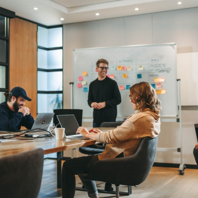 Professionals in a diverse group collaborate in a boardroom, engaging in a lively brainstorming session. They discuss ideas, showcasing teamwork and creativity. 