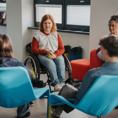 Young female student using wheelchair collaborates with classmates in the school library.
