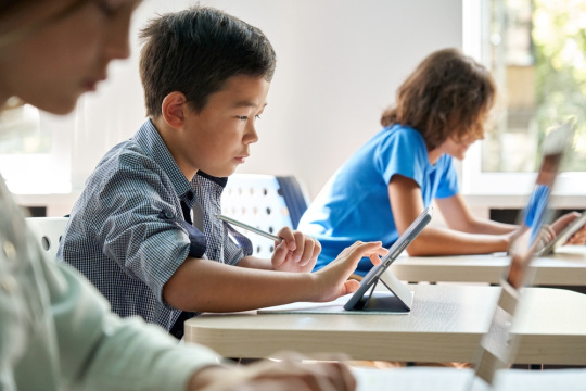 Focused school boy uses a digital tablet in the classroom.