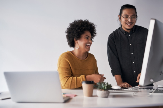 Smiling man and woman at desk for online brainstorming session regarding software development
