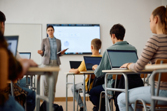 High school student and his classmates learning computer coding on a laptops in the classroom.