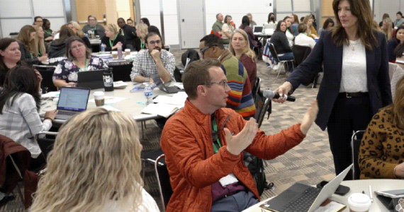 People at tables at a conference.