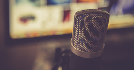 Image of a microphone in front of a computer screen