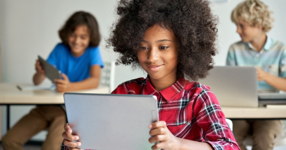 Smiling girl reads from her digital tablet.