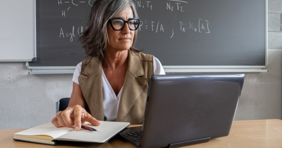 A female science teacher working with a laptop in a high school office.  