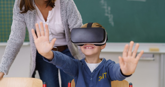 Boy using virtual reality goggles in the classroom