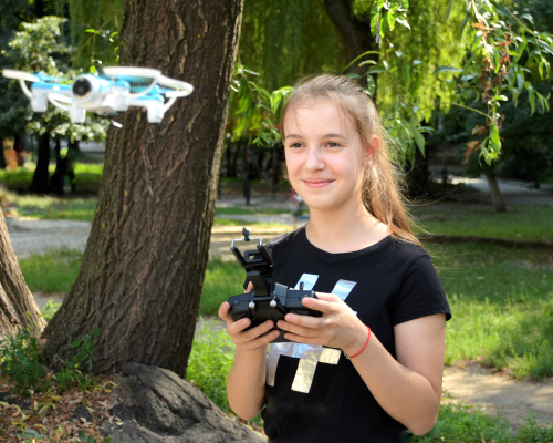Smiling teen girl using drone. Blurred flying copter on front.