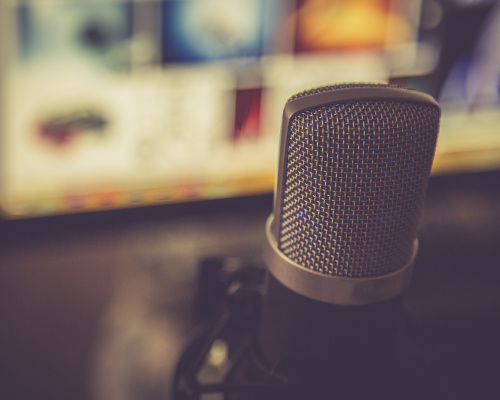 Image of a microphone in front of a computer screen