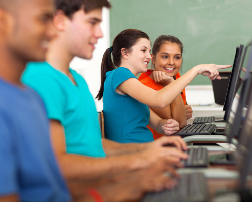 Teenage high school girl helping a classmate with computer in class