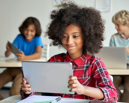 Smiling girl reads from her digital tablet.