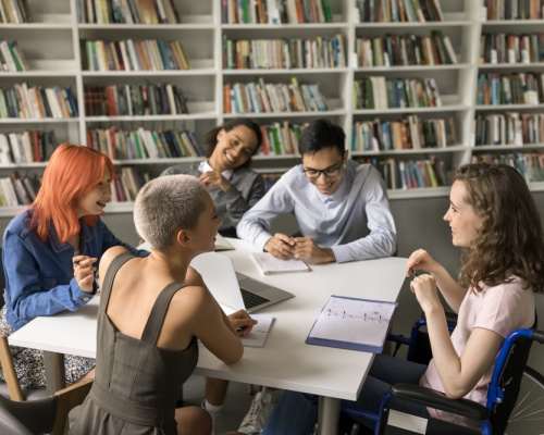A happy group of students study in a school library, talking and laughing.