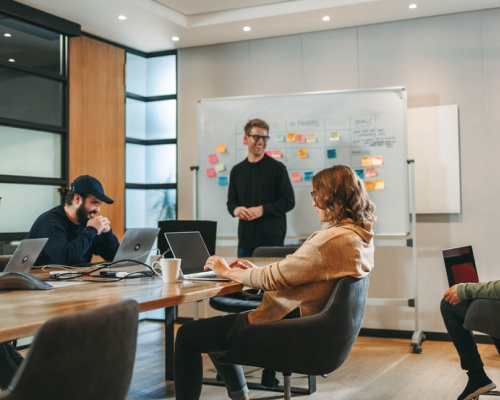 Professionals in a diverse group collaborate in a boardroom, engaging in a lively brainstorming session. They discuss ideas, showcasing teamwork and creativity. 