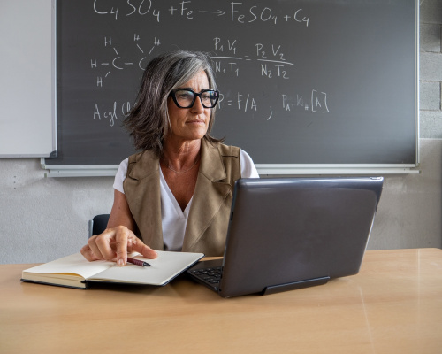 A female science teacher working with a laptop in a high school office.  