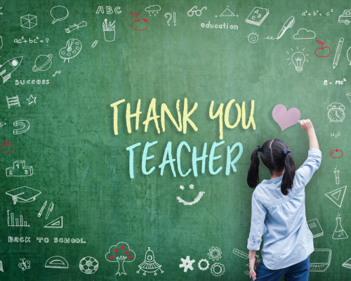 Students writes Thank You Teacher on a chalkboard